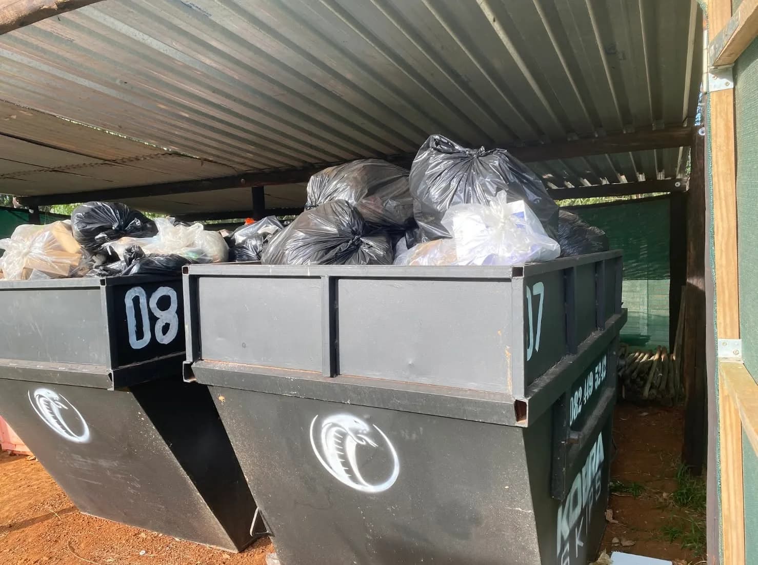Two Kobra Skips filled with black bags at the yard — general waste collected from residential jobs.