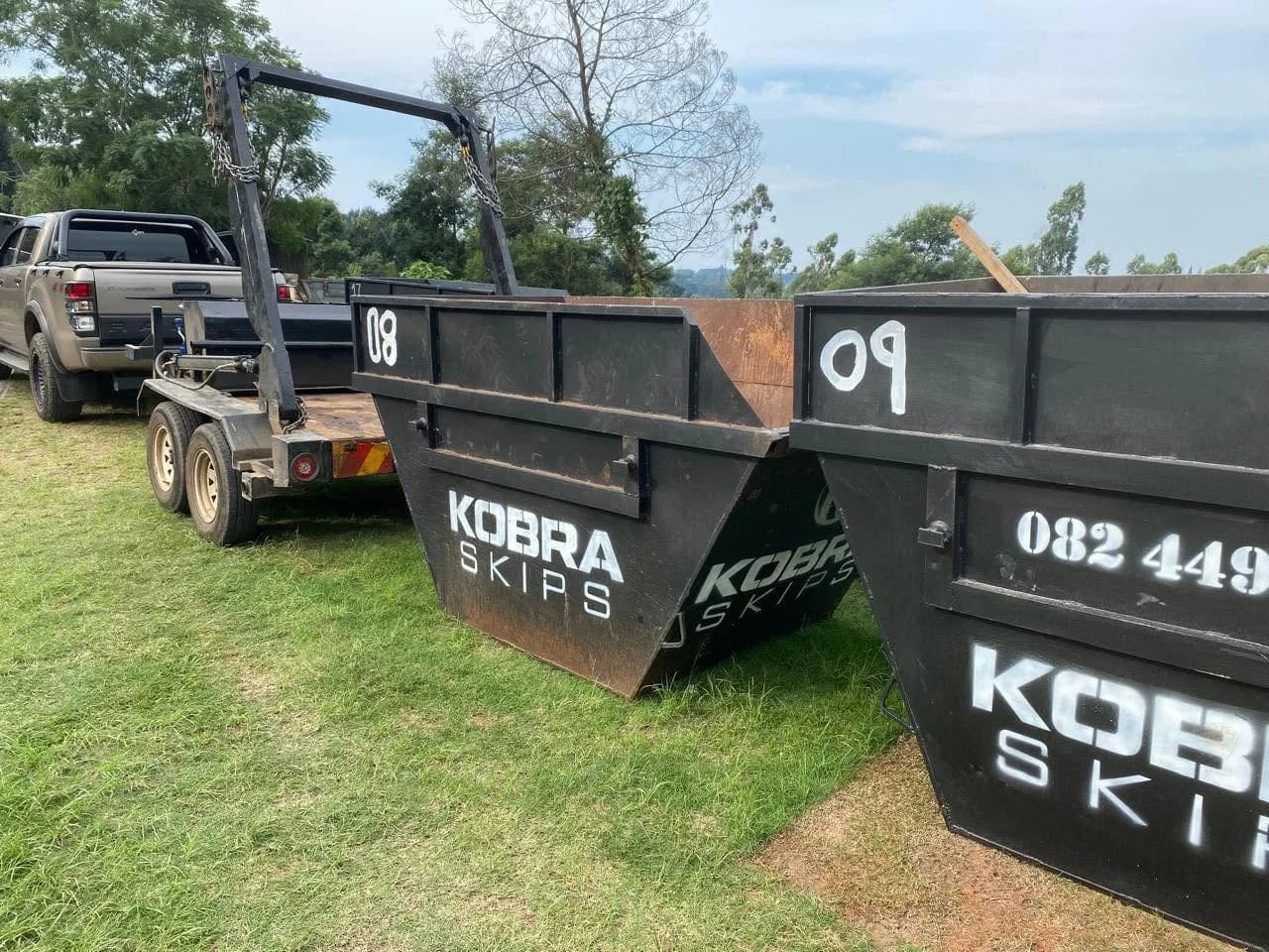 Two Kobra Skips unloaded on a lawn — back-to-back skips for a larger residential clearance job.