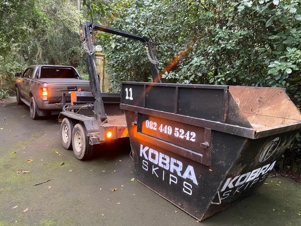 Kobra Skip number 11 being dropped at a leafy residential driveway in Kloof.